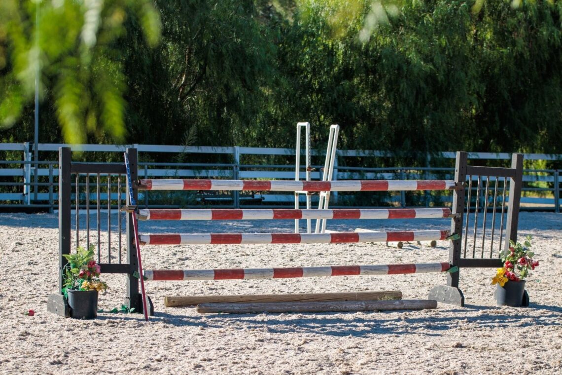 Obstacle d’équitation composé de barres rouges et blanches dans une carrière